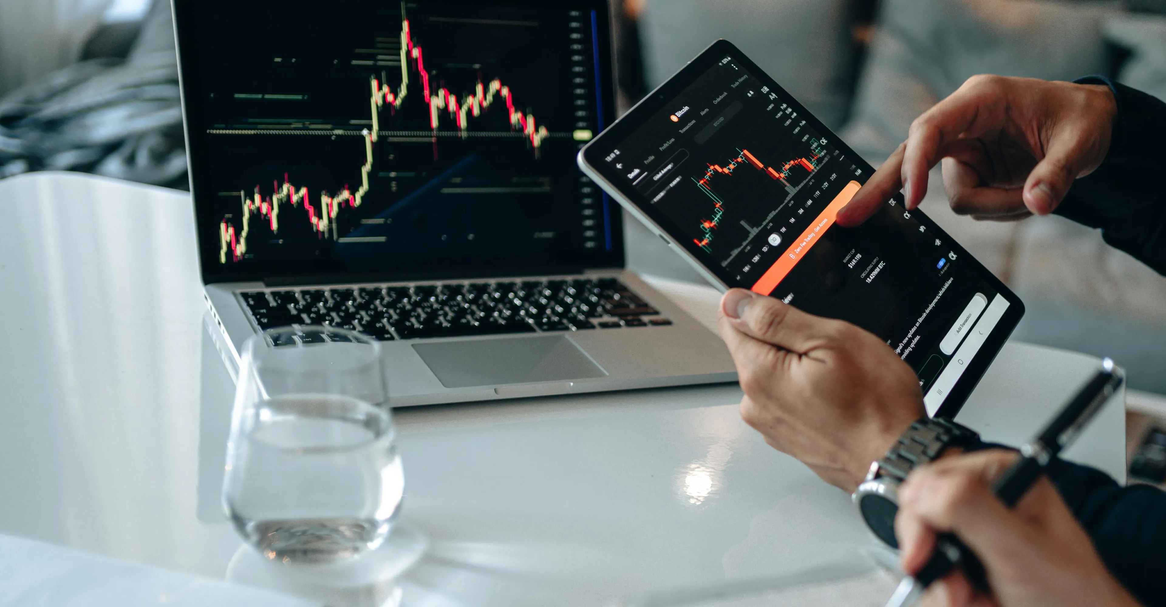 Trader reviewing market data on a laptop and a phone